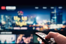 Watching movie stream service on tv. Video on demand subscription service and platform in television. Streaming series, films and shows online. Man using remote control.