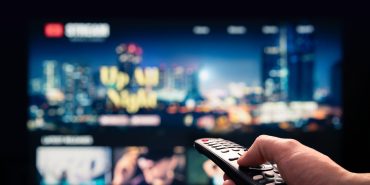 Watching movie stream service on tv. Video on demand subscription service and platform in television. Streaming series, films and shows online. Man using remote control.