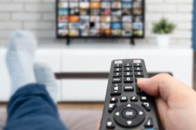 Man watching TV, lying on sofa, legs on table