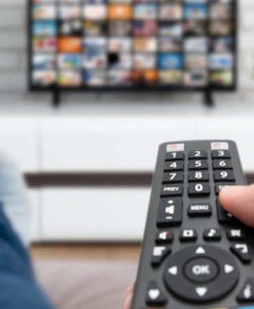 Man watching TV, lying on sofa, legs on table