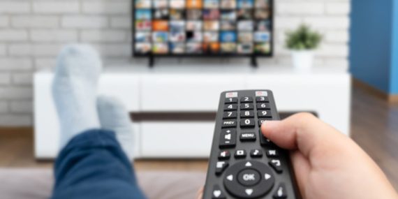 Man watching TV, lying on sofa, legs on table